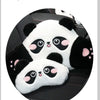 A white and black panda plush cushion designed as a car headrest or lumbar support for travel.