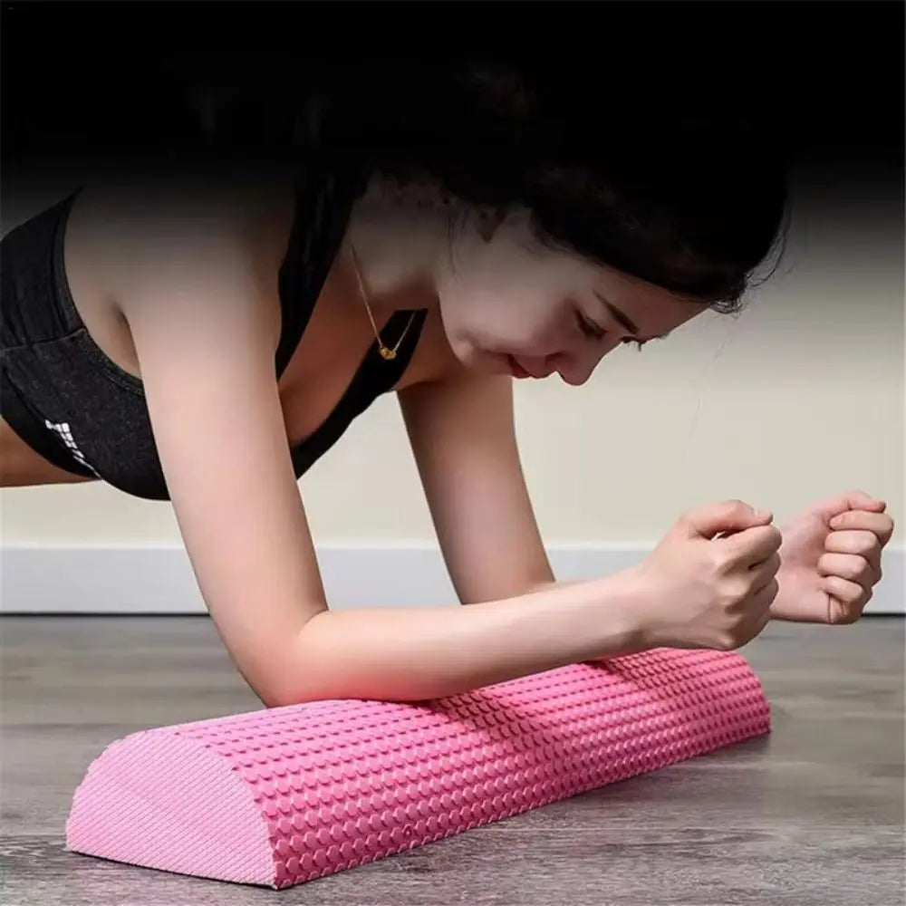 A person is using a pink half-round EVA foam roller for muscle relief or yoga balance.