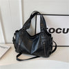 Black vintage leather tote bag with multiple pockets displayed on a white surface.