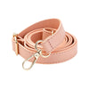 A roll of light pink adjustable leather bag strap replacement with a gold-toned buckle.
