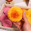 Eine Hand hält einen leuchtend orangefarbenen, strukturierten Kartoffel-Stressball-Fidget-Spielzeug in einer Pappschale.