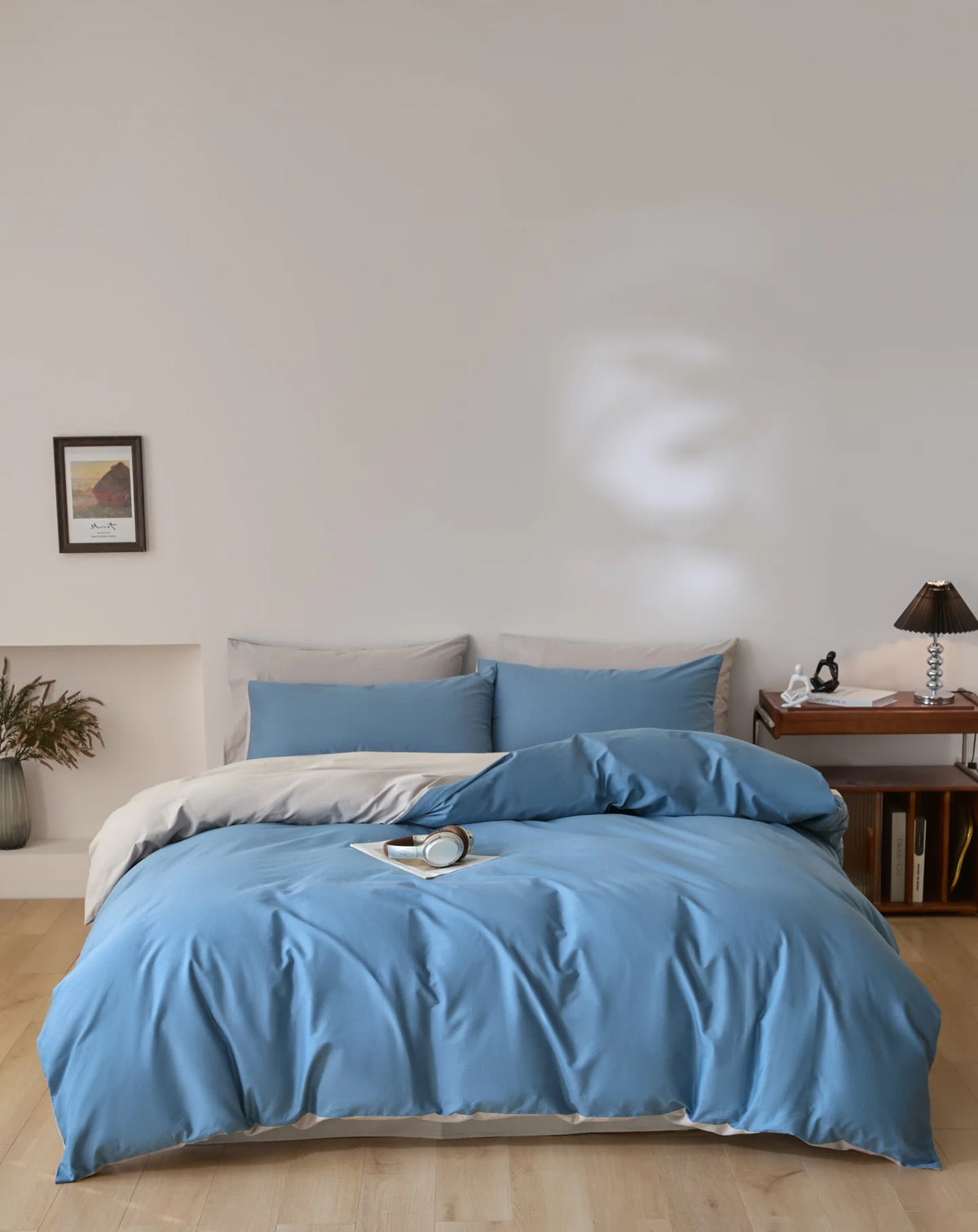 A light blue quilted duvet cover set with matching pillowcases displayed on a bed against a white wall.