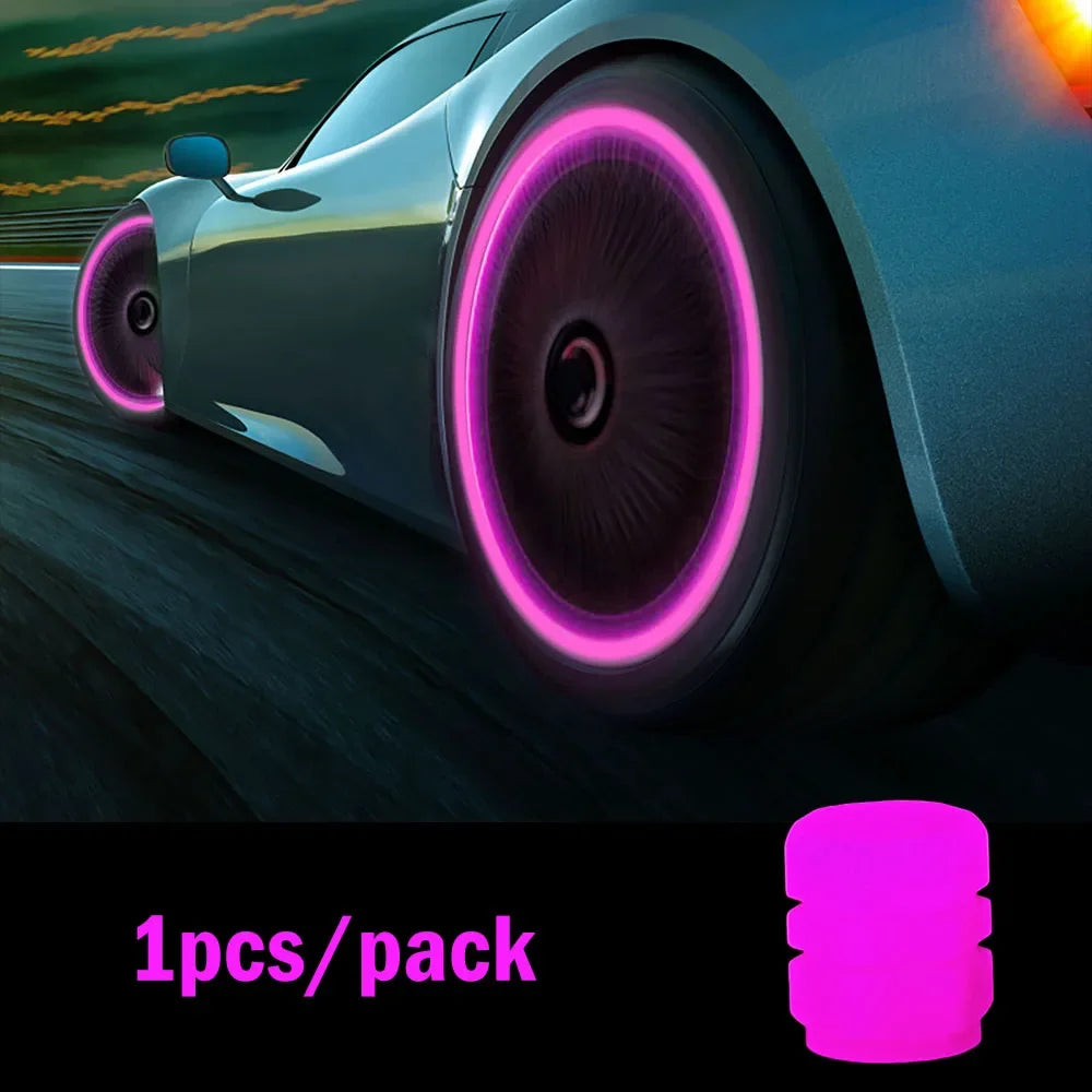 Close-up of a car tire with luminous pink glow-in-the-dark valve caps on a dark road at sunset.