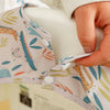 A hand is adjusting a long-sleeve waterproof baby bib with an animal design pattern.