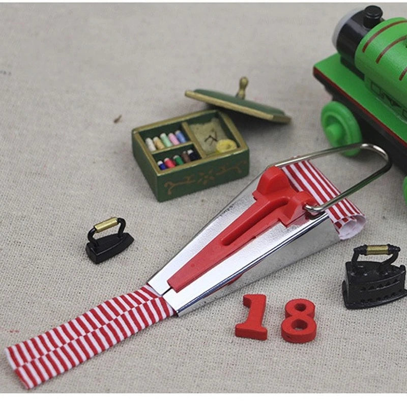 A stainless steel bias tape maker set with four different sized tape rollers and a green tool visible on a light background.