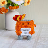 Handmade crochet dumpster fire doll with bright orange body and floral accents, featuring an emotional support message.