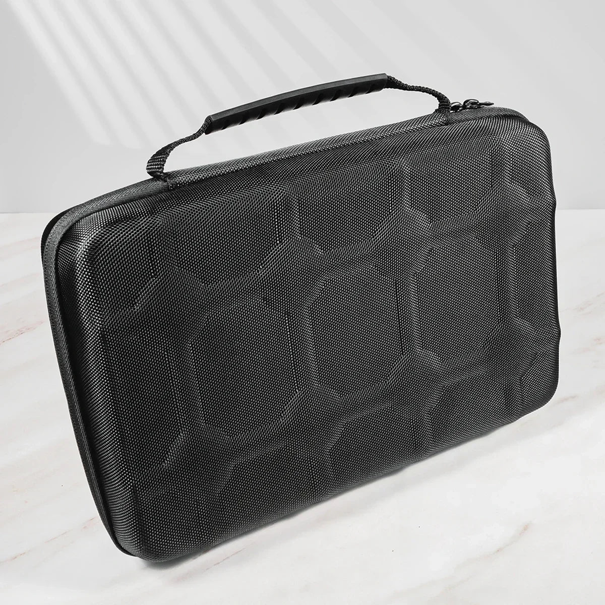 A black portable leather watch travel case with a textured surface is shown on a white marble surface.