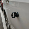Close-up of a black car dent puller kit handle mounted on the side of a white car.