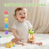 A smiling baby holding a green animal rattle teether toy on a white fluffy surface.