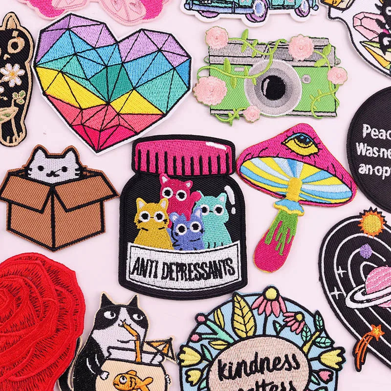 A collection of colorful cartoon cat embroidery patches and iron-on designs featuring various expressions and themes.