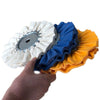 A hand is holding an 8-inch 16-ply airway buffing wheel for metal polishing, showing white, blue, and orange buffing pads.