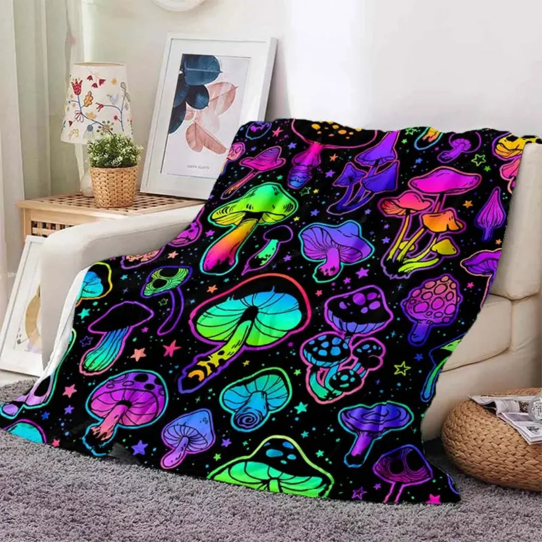 A colorful mushroom print flannel throw blanket displayed on a light-colored sofa.