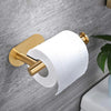 A brass adhesive stainless steel toilet paper holder with a white roll mounted on a gray wall.