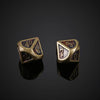 A pair of bronze metal polyhedral dice, showing various numbers and symbols, resting on a dark reflective surface.