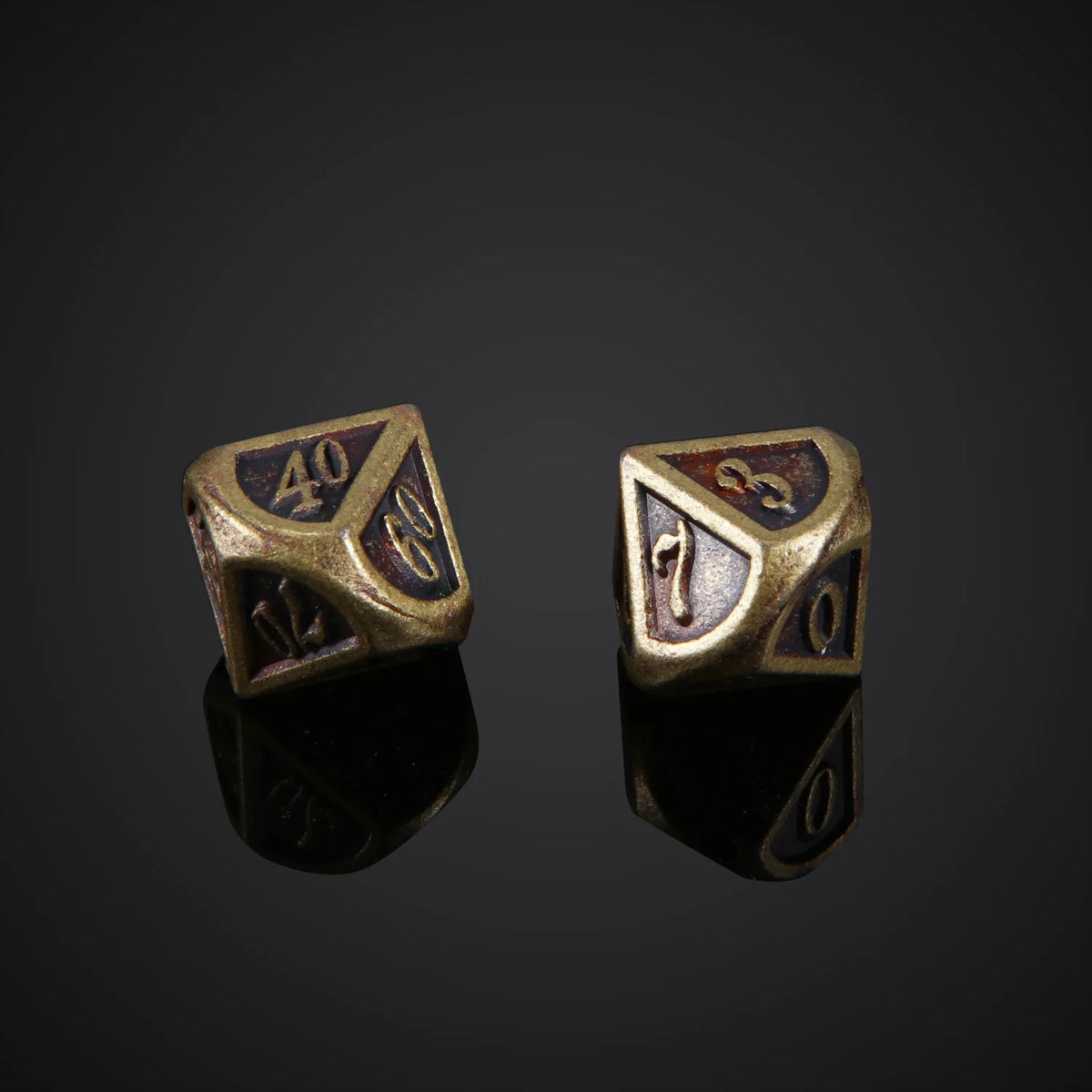 A pair of bronze metal polyhedral dice, showing various numbers and symbols, resting on a dark reflective surface.