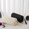 A beige quilted storage bag and a black quilted storage bag are displayed on a white surface.