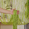 A hand is holding a vertical curtain made of long, shimmering lime green tassels hanging in the air.