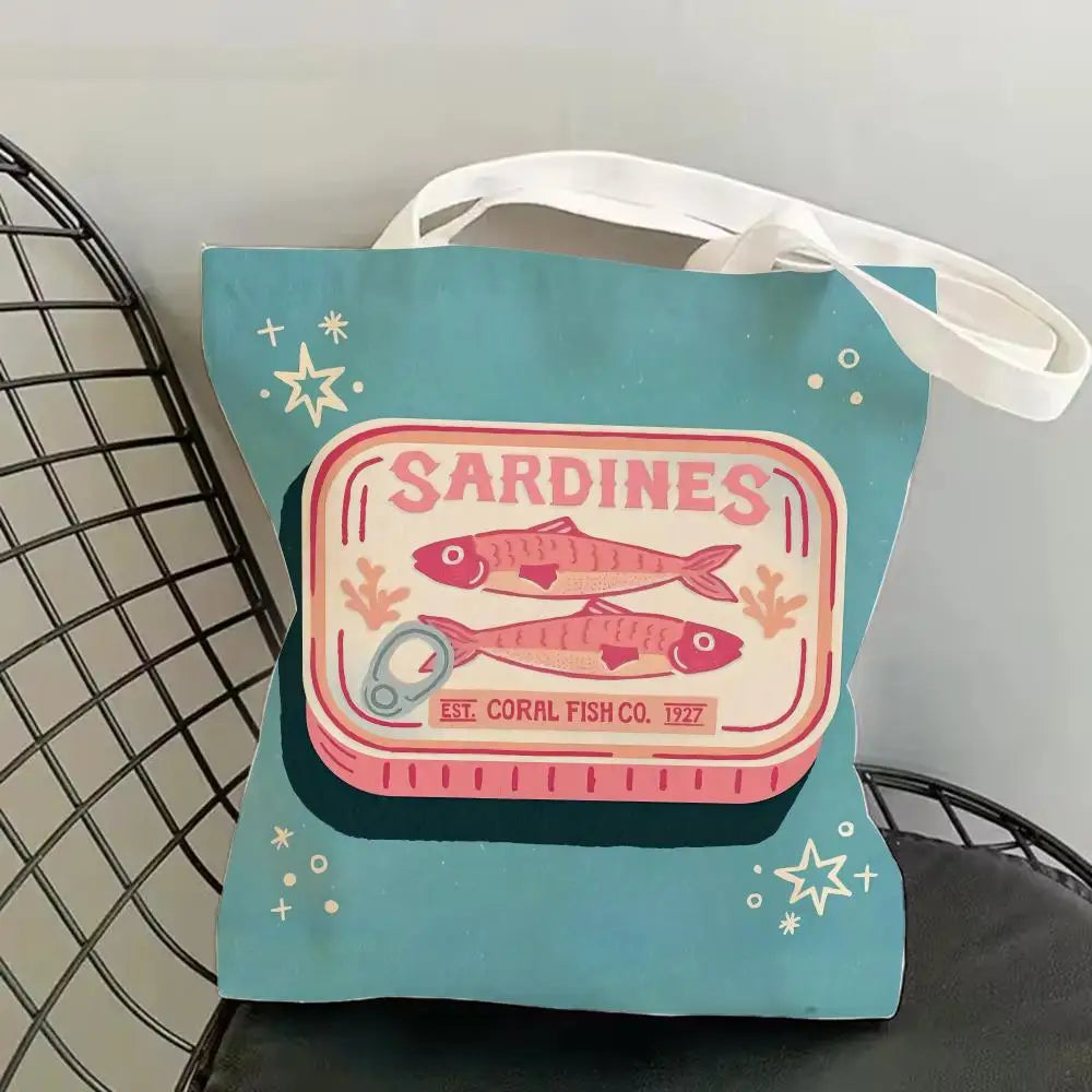 A teal canvas tote bag featuring a graphic print of sardines and starfish.