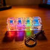 A set of clear LED macaron keyboard fidget toys attached to a silver keychain, resting on a wooden surface.