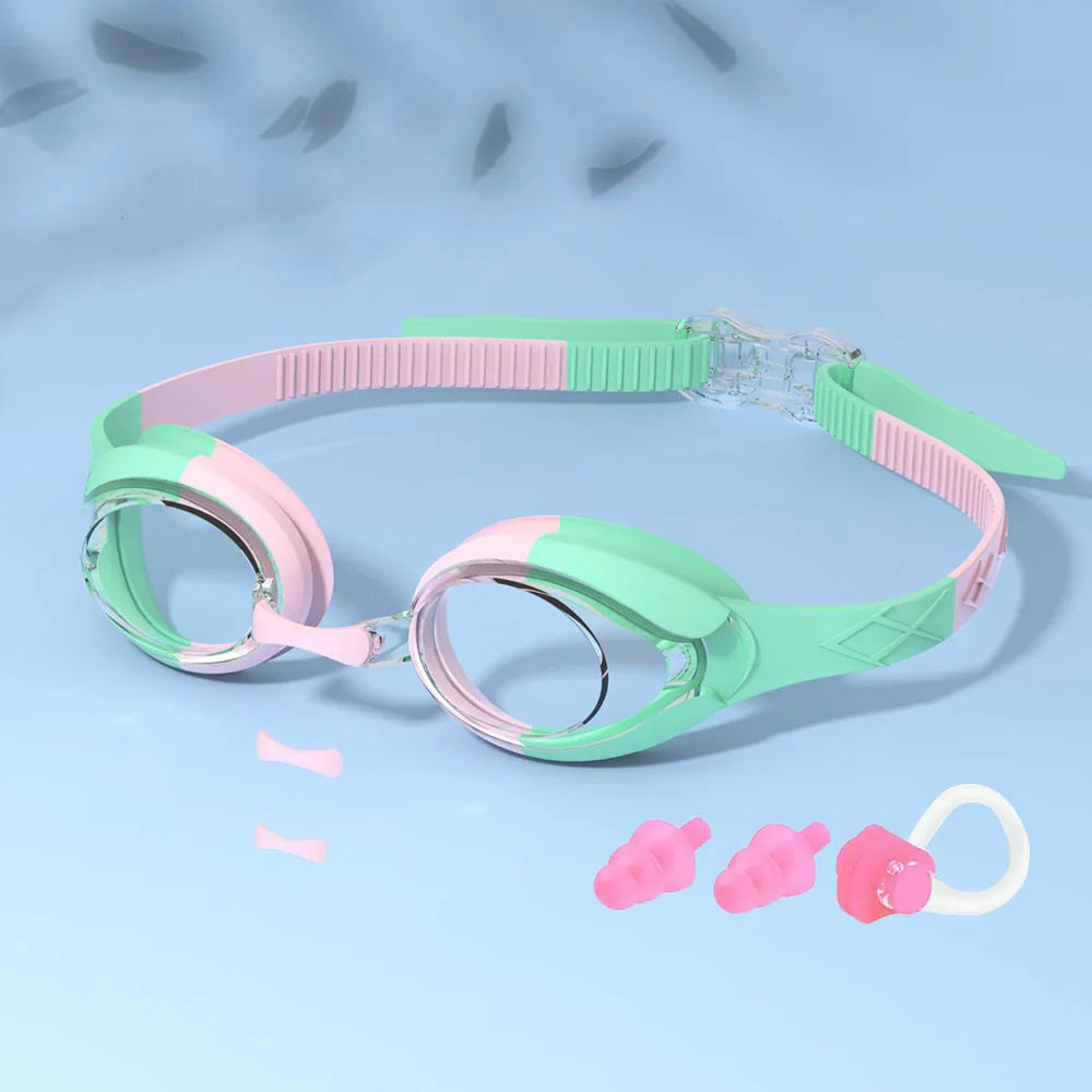 Une paire de lunettes de natation roses et vertes pour enfants, affichées sur un fond bleu clair.