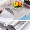 Self-adhesive aluminum foil kitchen backsplash protector showing various textures and a roll of protective film.