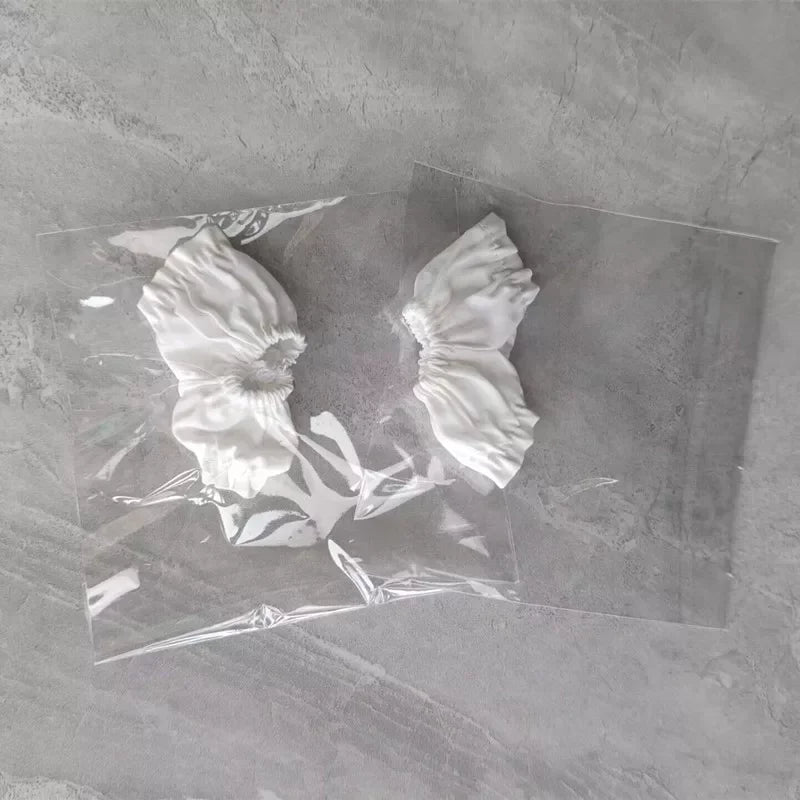 A clear plastic bag contains two white, ruffled collectible figurines.