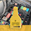 A yellow automotive fuse tester tool is shown inserted into a black fuse box with various fuses and relays.