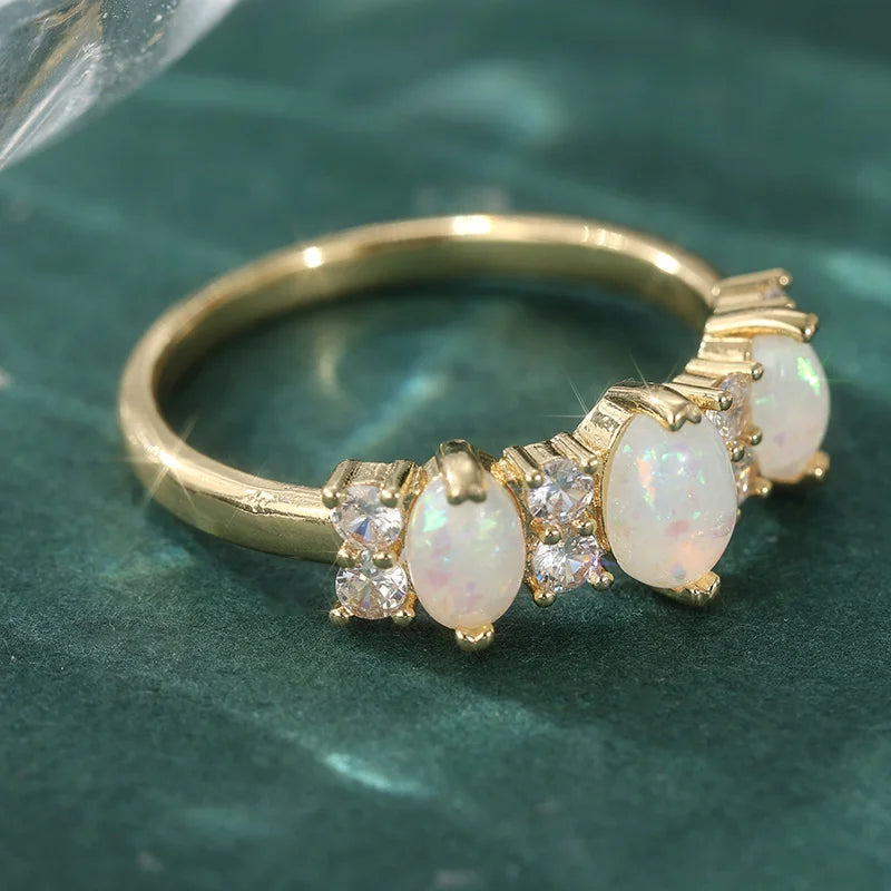 Bague plaquée or featuring des pierres d'opale synthétique ovales entourées de petits diamants clairs.