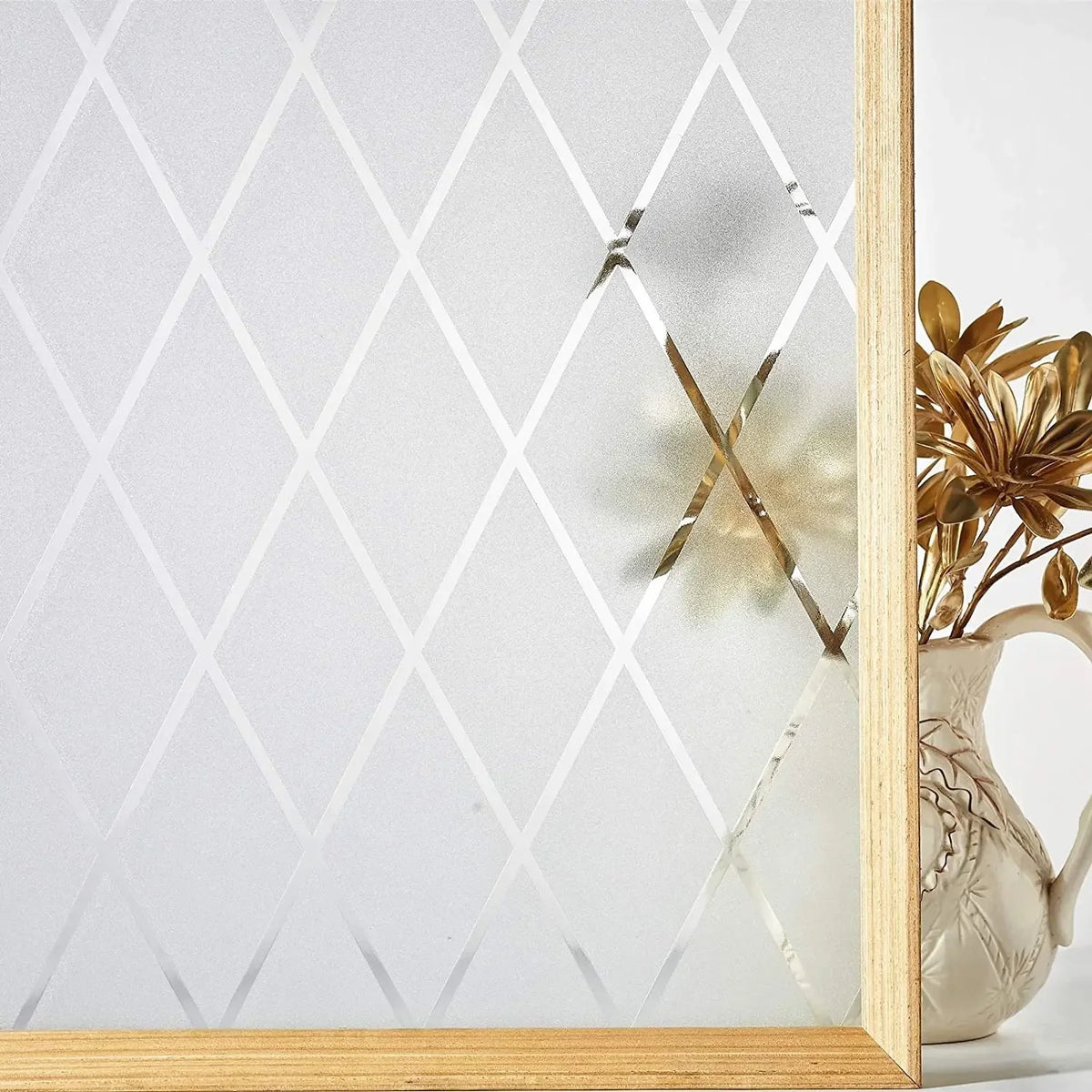 A close-up of a frosted stripe privacy window film displayed in a wooden frame with dried floral accents.