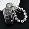 A silver car key fob attached to a chain and a bracelet of chrome-plated metal balls.