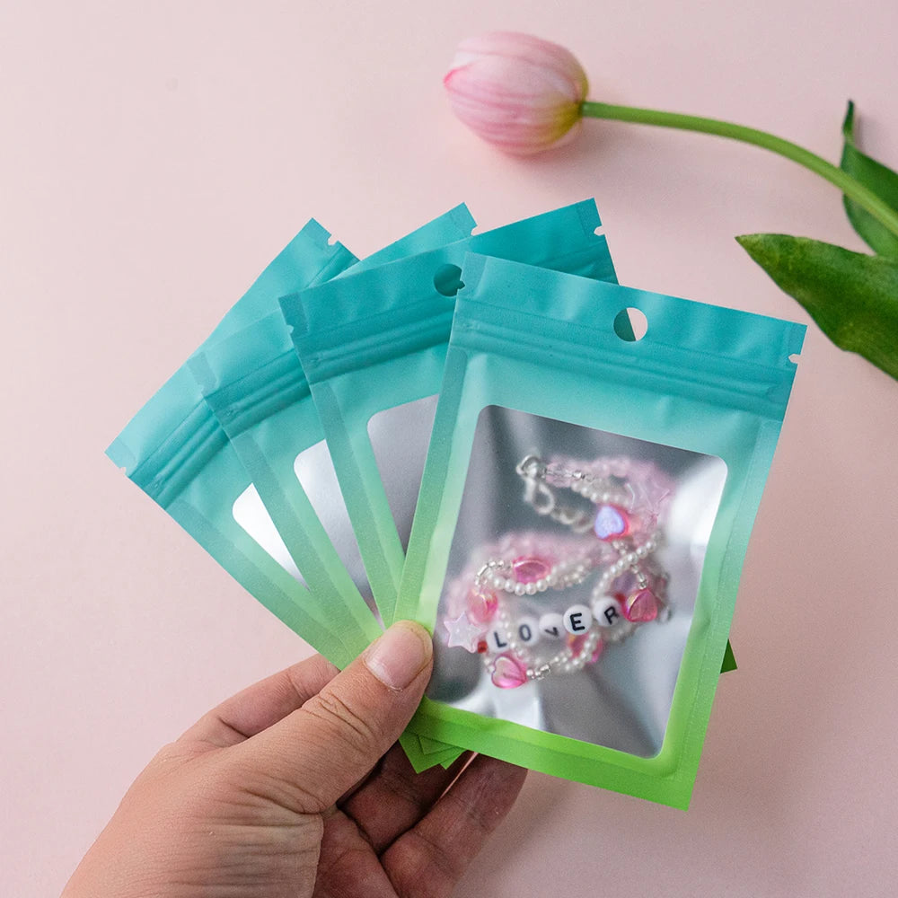 A hand holds a clear ziplock pouch containing a pink and white beaded necklace.