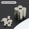 A collection of silver disc magnets stacked and scattered on a dark surface.