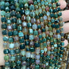 A close-up of natural stone square faceted beads in various shades of green, blue, and pink clustered on a hand.