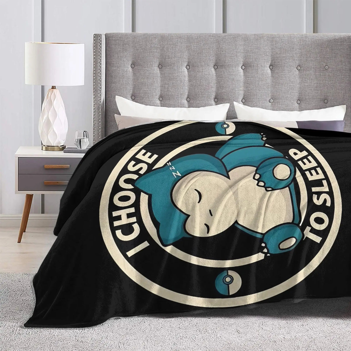 A black throw blanket featuring a graphic of a sleeping Snorlax face in teal and cream colors.