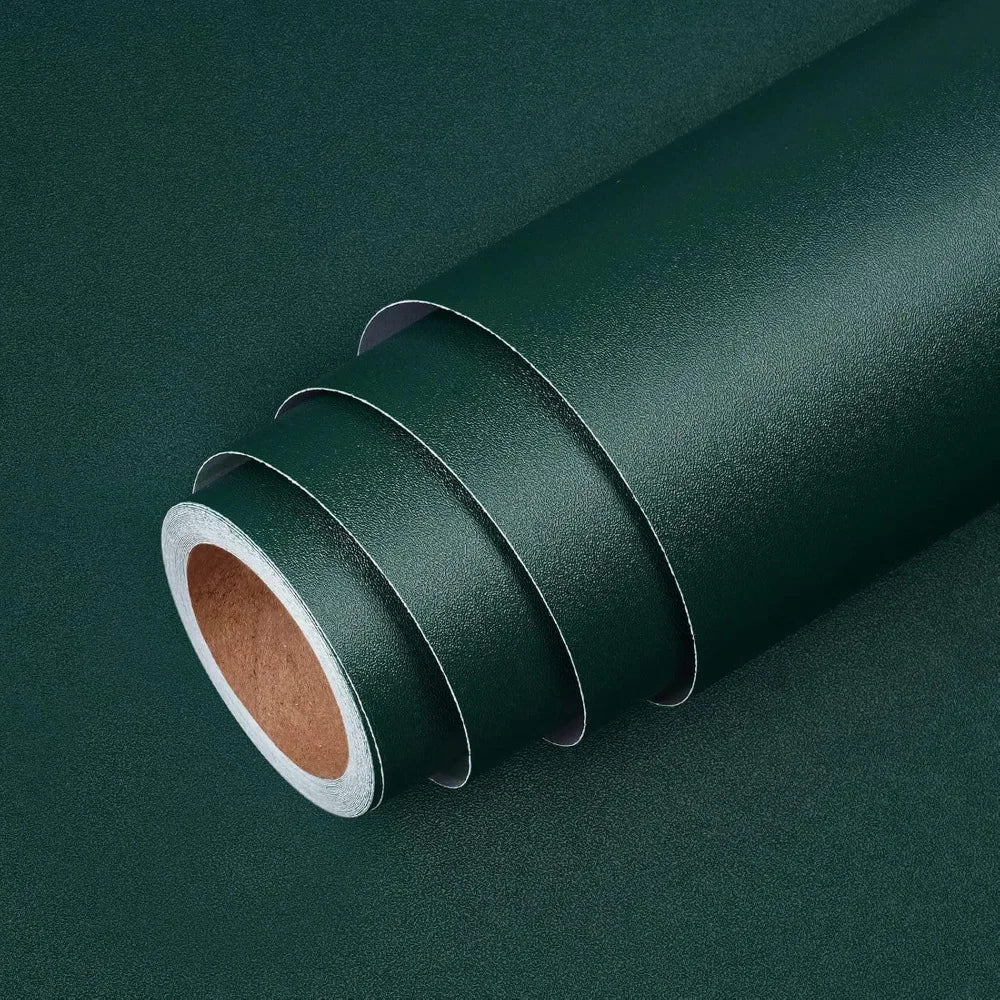 A roll of dark green self-adhesive peel-and-stick wallpaper shown diagonally on a dark surface.