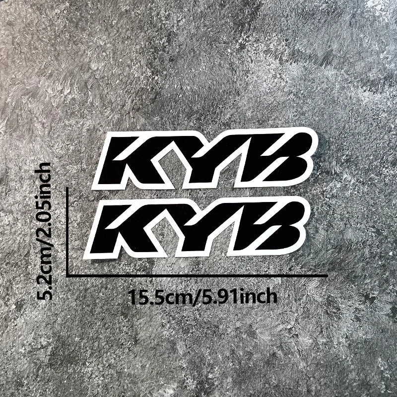 Black and white KYB motocross motorcycle fork stickers displayed on a gray textured surface.