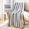 A gray and white striped microfiber bath towel draped over a wooden stand.