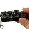 A hand holds a black LED mechanical keychain fidget toy with custom keycaps.