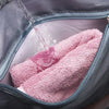 A pink towel is being rinsed inside a gray travel duffel bag with a zipper open.