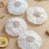White waterproof shower caps or bathings for hair care displayed on a wooden surface.