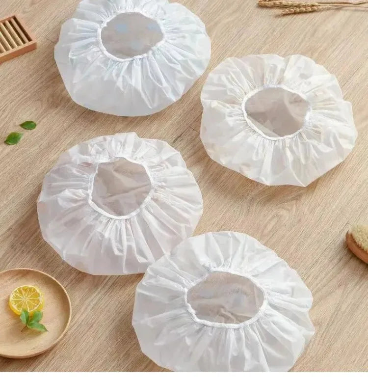White waterproof shower caps or bathings for hair care displayed on a wooden surface.