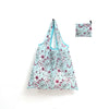 A light blue floral reusable shopping tote bag with a matching small carry pouch.