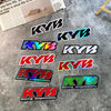 A collection of black and colored KYB motocross motorcycle fork stickers displayed on a gray surface.