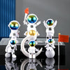 A set of handcrafted astronaut figurines in white and gold resin displayed on a dark surface.