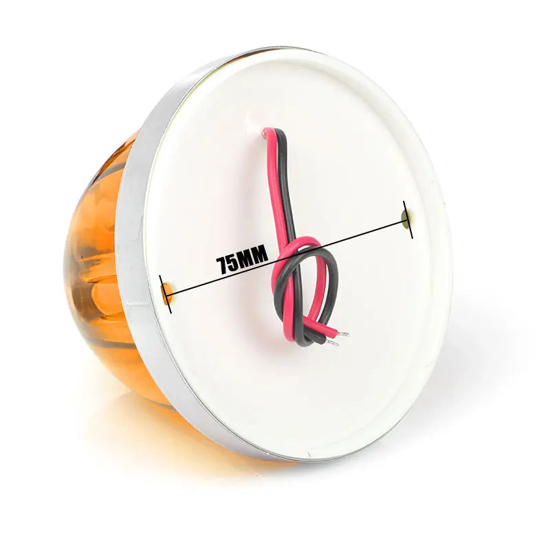 A round white light housing with an orange lens and a pink electrical wire visible inside.
