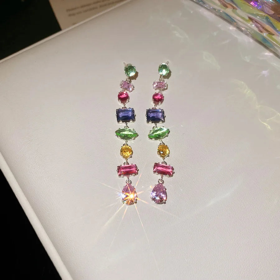 Une paire de colliers en cristal colorés avec des tons de vert, bleu, jaune et rose sur placage doré.