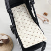 A beige padded seat cushion with a rainbow pattern is shown inside a black baby stroller seat.