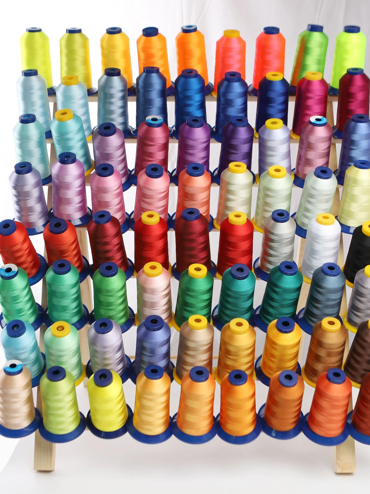 A display of various multi-colored polyester embroidery threads in spools arranged horizontally.