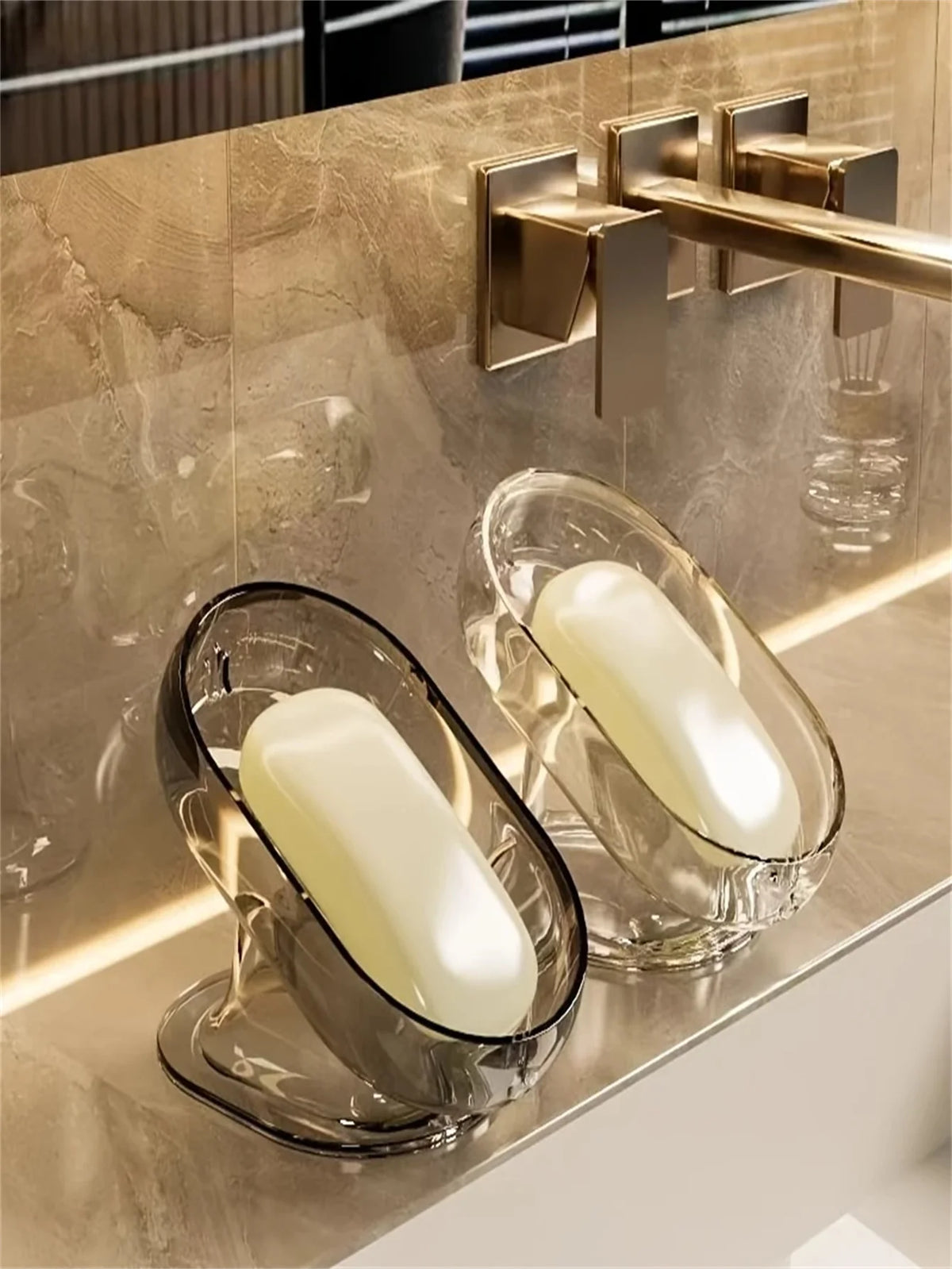 Elegantes, leichtes Glas-Seifenschale mit einer weißen Seife auf einer goldfarbenen Arbeitsplatte.