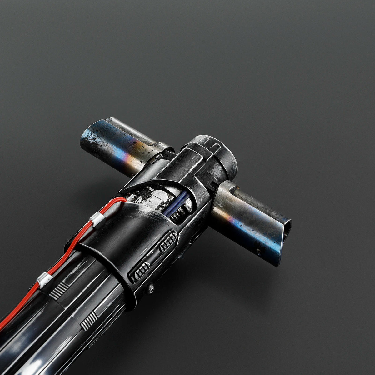 A close-up view of a black metal lightsaber with a blue hilt and red accents, showing motion control components.